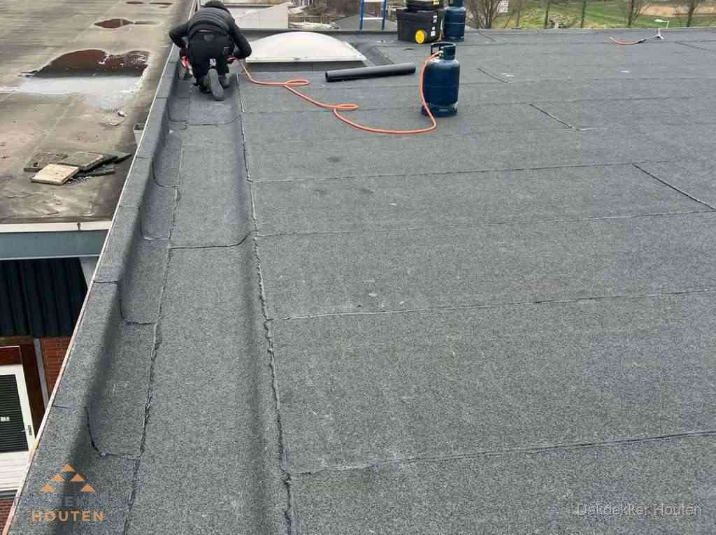 Dakdekker repareert bitumen dakbedekking op groot plat dak in Houten Dakdekker repareert bitumen dakbedekking op groot plat dak in Houten